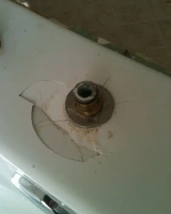 A cracked tub deck around a corroded faucet fitting before repair.