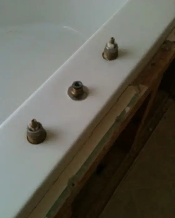 The same tub deck with the faucet stems removed and the damage cut back, prepared for repair.