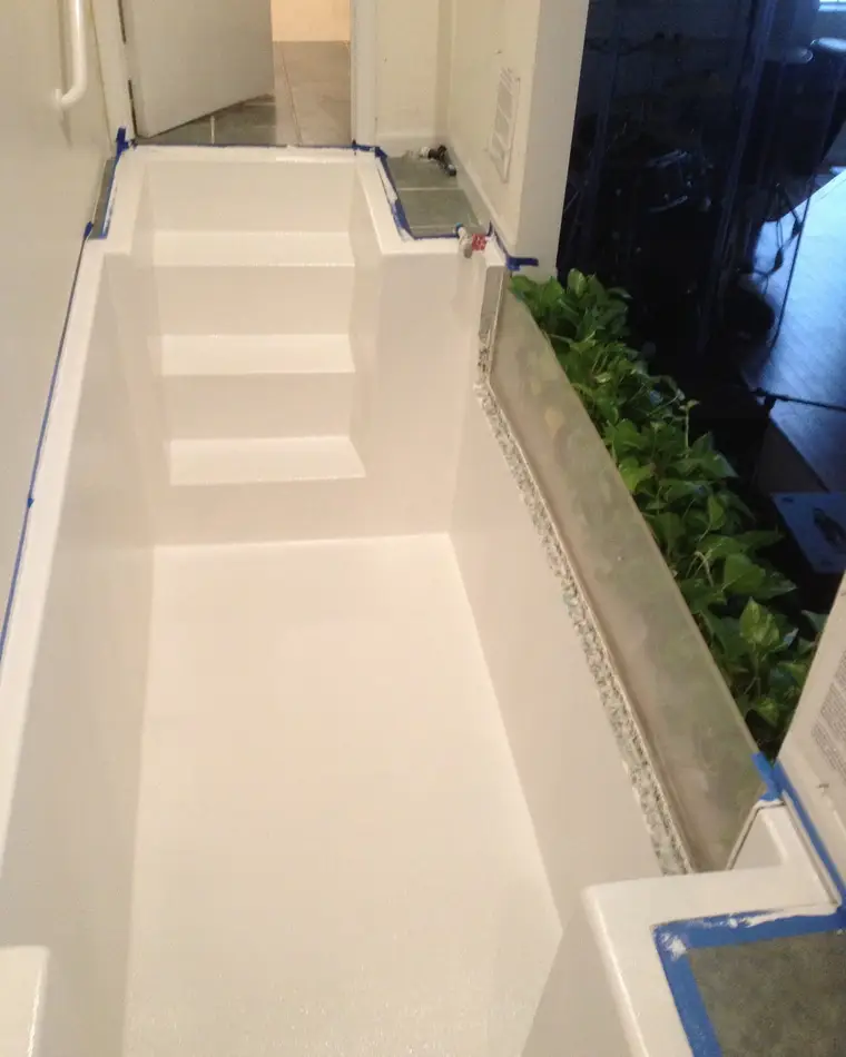 The same baptismal pool after refinishing, re-coated white with the surround masked off.