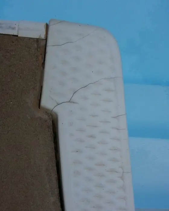 A cracked corner on a moulded step unit before repair, the broken edge open to the substrate.