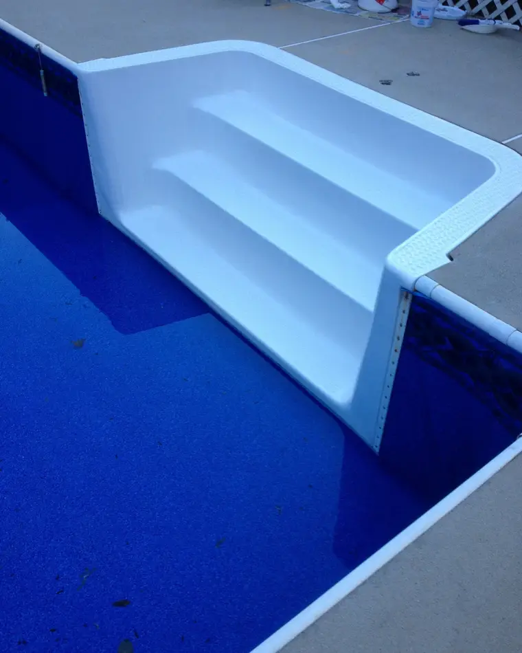 The same pool steps after refinishing, re-coated to an even white against a blue liner.