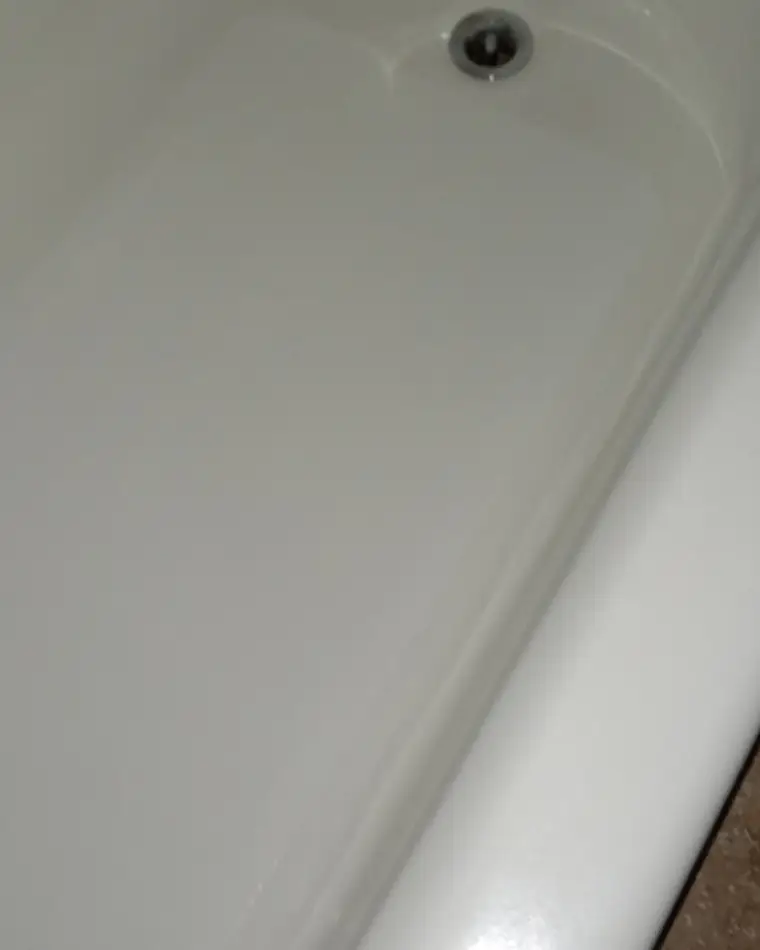 The same bathtub after refinishing, the floor an even white with the worn pads and staining gone.